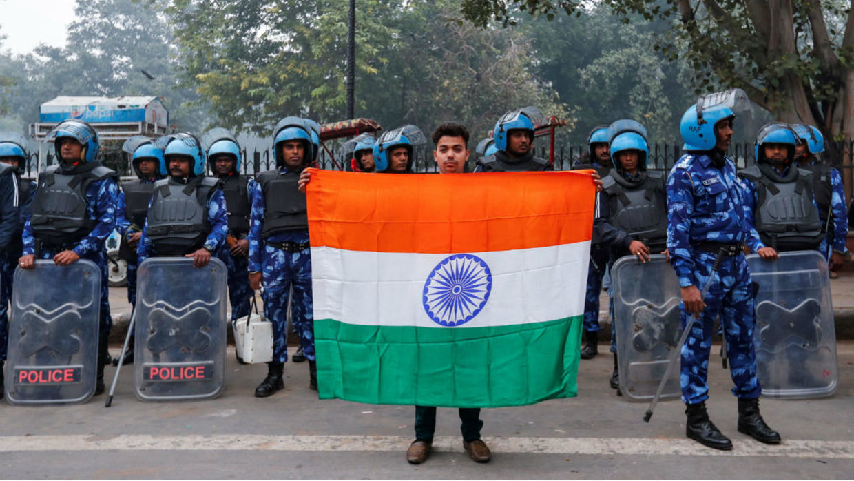 Mohammad Anas Qureshi, 20, who is a fruit vendor, poses for photo with the national flag of India in front of riot police during a protest against a new citizenship law in Delhi, India, December 19, 2019. Danish Siddiqui, Reuters