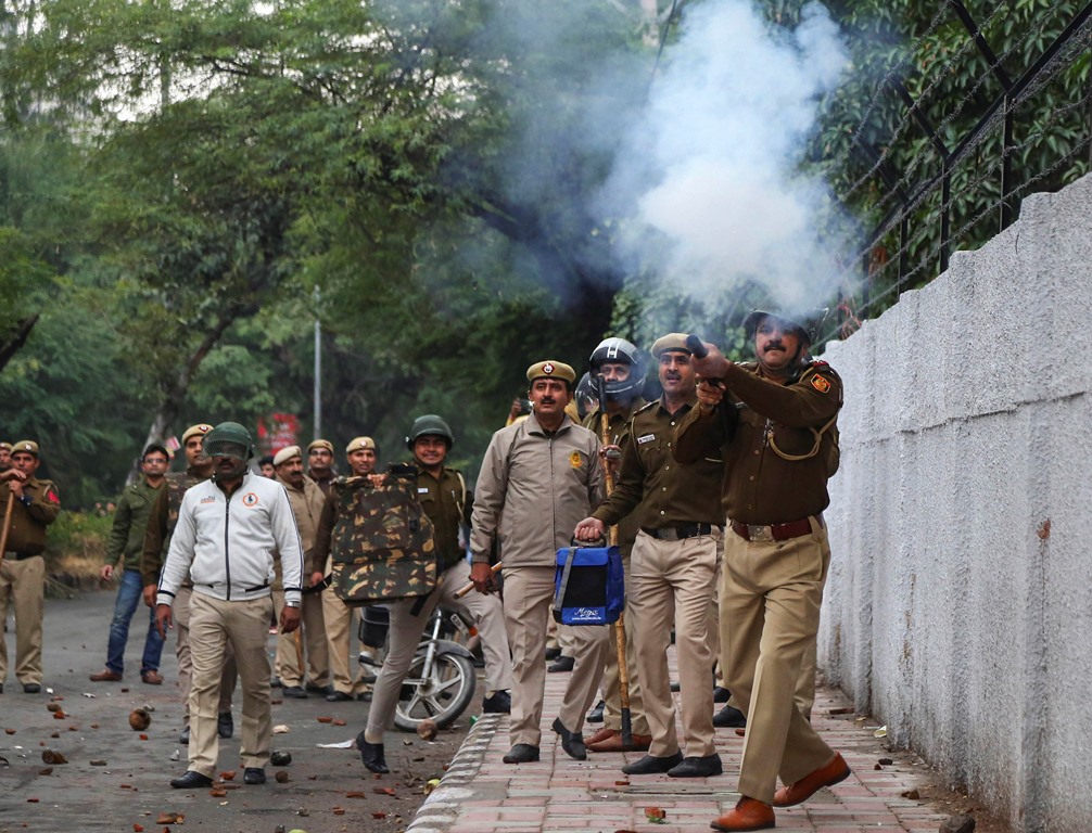New Delhi: A police personnel fires tear gas as students of Jamia Millia Islamia University stage a protest against the passing of Citizenship Amendment Bill, in New Delhi, Friday, Dec. 13, 2019. (PTI Photo) (PTI12_13_2019_000384B)