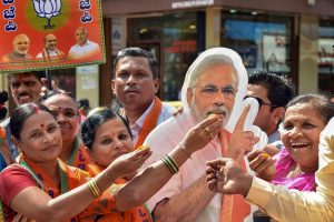 Hubballi: BJP supporters offer sweets to a cut-out of Prime Minister Narendra Modi after the party won in 12 out of 15 assembly constituencies of Karnataka securing the position of Yediyurappa-led BJP government in the state, in Hubballi, Monday, Dec. 9, 2019. (PTI Photo) (PTI12_9_2019_000091B)