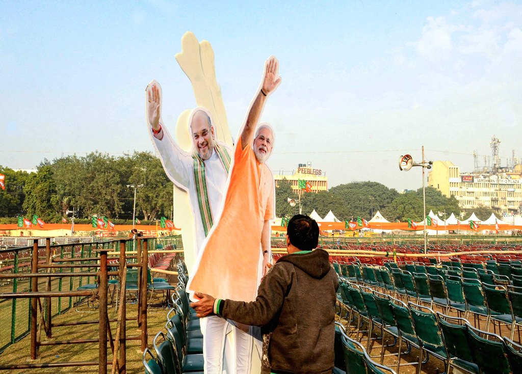 New Delhi: A workers carries cut-outs of Prime Minister Narendra Modi and Union Home Minister Amit Shah on the eve of  BJP rally at Ramlila Maidan in New Delhi, Saturday, Dec. 21, 2019. (PTI Photo)(PTI12_21_2019_000185B)