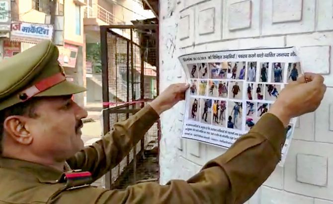 Gorakhpur: A police personnel sticks a collage of people involved in violence during protest on Friday after Juma Namaz against CAA and NRC, obtained from video footage and CCTV camera footage, in Gorakhpur, Saturday, Dec. 21, 2019. (PTI Photo) (PTI12_21_2019_000219B)