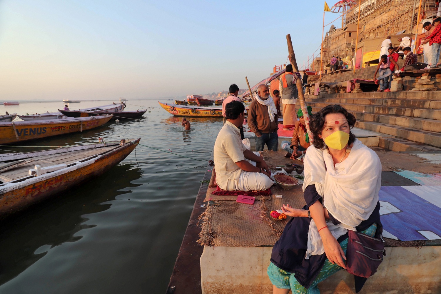 Varanasi: A woman wearing a protective mask sits near an near deserted bank of River Ganga in the wake of coronavirus pandemic, in Varanasi, Friday, March 20, 2020. (PTI Photo)(PTI20-03-2020_000035B)