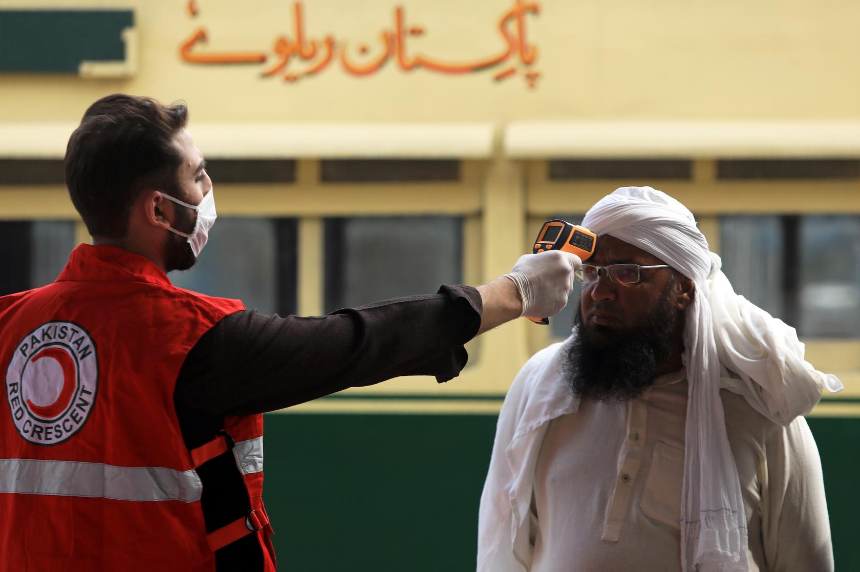 A worker checks a man's temperature following an outbreak of the coronavirus disease (COVID-19), at a railway station in Peshawar, Pakistan. (Reuters Photo)