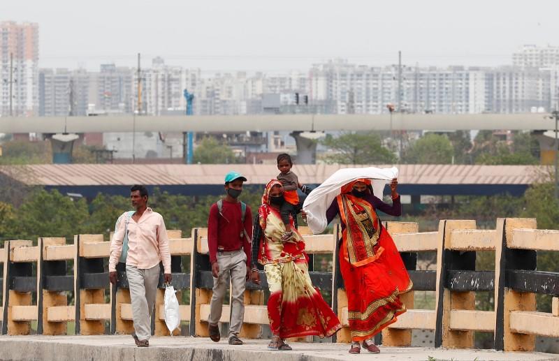 A migrant worker carries her daughter as she walks on a highway with others looking out for a transport to return to their villages, after India ordered a 21-day nationwide lockdown to limit the spreading of coronavirus disease (COVID-19), in Ghaziabad, on the outskirts of New Delhi, March 26, 2020. REUTERS/Adnan Abidi