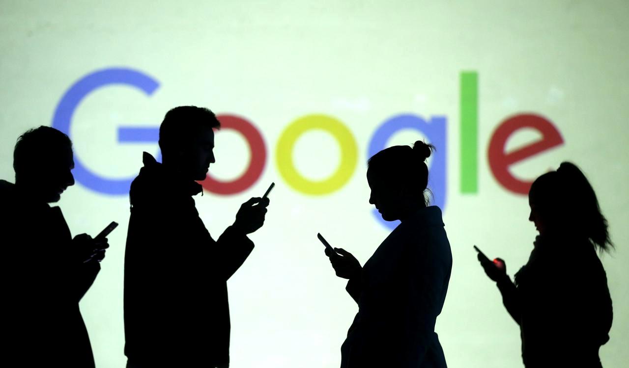 Silhouettes of mobile users are seen next to a screen projection of Google logo in this picture illustration taken March 28, 2018. REUTERS/Dado Ruvic