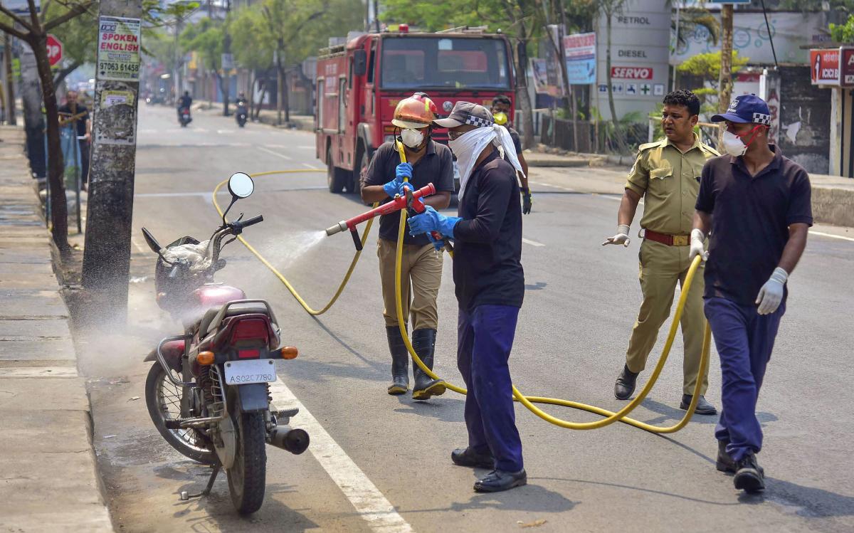SDRF and Fire brigade officials spray disinfectant on a bike in the wake of the coronavirus, in Nagaon. PTI Photo