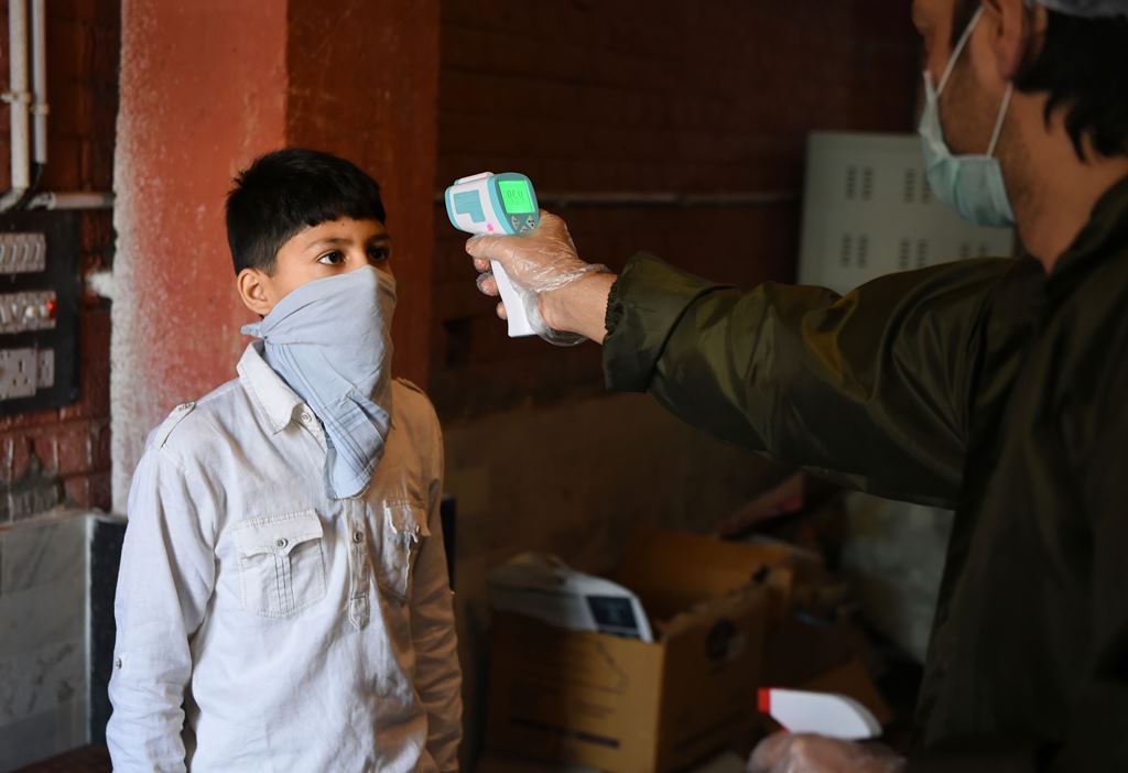 Srinagar: A man checks the temperature of a boy who came to buy sweets at a bakery shop ahead of Eid-ul-Fitr, during ongoing COVID-19 lockdown, in Srinagar, Wednesday, May 20, 2020. (PTI Photo/S. Irfan) (PTI20-05-2020 000153B)