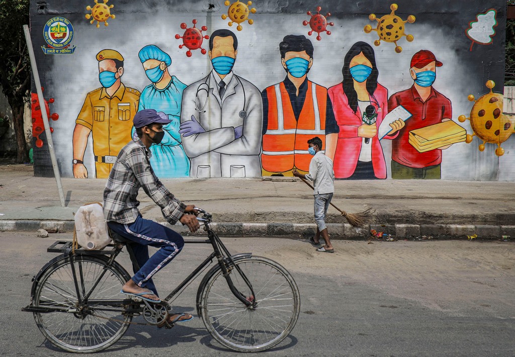 New Delhi: A cyclist rides past a mural that reads A Big Salute To Corona Warriors, during ongoing COVID-19 lockdown, in New Delhi, Sunday, May 31, 2020. (PTI Photo/Ravi Choudhary)(PTI31-05-2020 000132B)