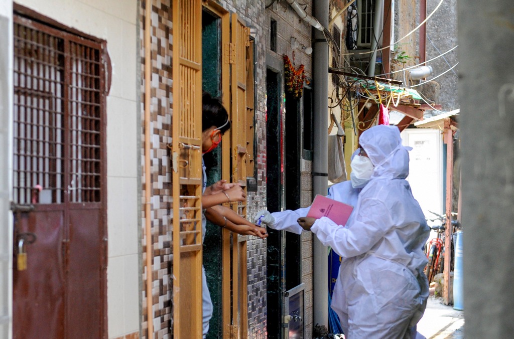 Mumbai: A health worker marks the hands of residents with home quarantine stamp, at Bhaji Galli Road no. 3 of Andheri East in Mumbai, Saturday, June 27, 2020. (PTI Photo)