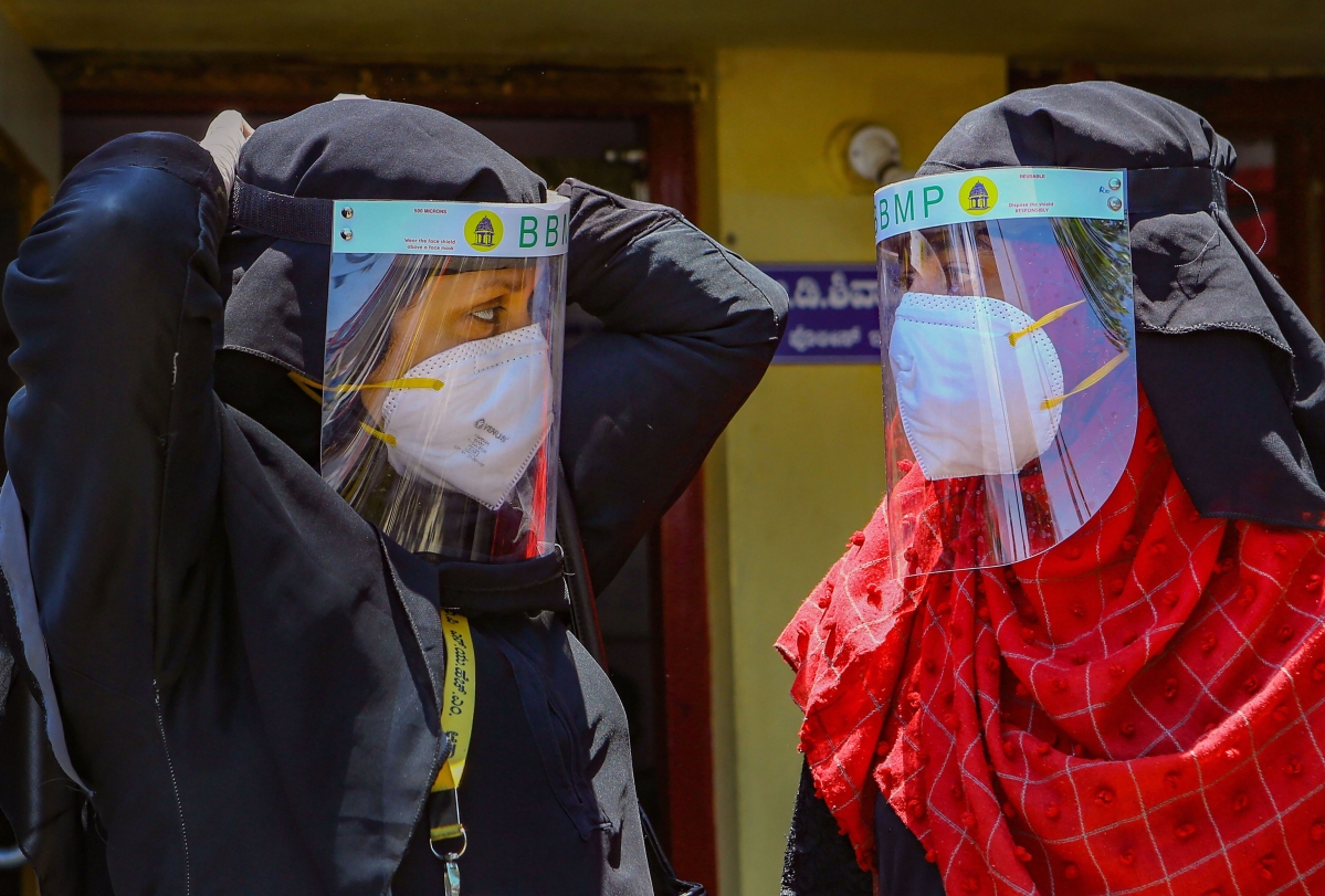 BBMP health workers adjust their visa shields before entering the areas of Padarayanapura in Chamarajapet during ongoing COVID-19 lockdown, in Bengaluru. (PTI) 