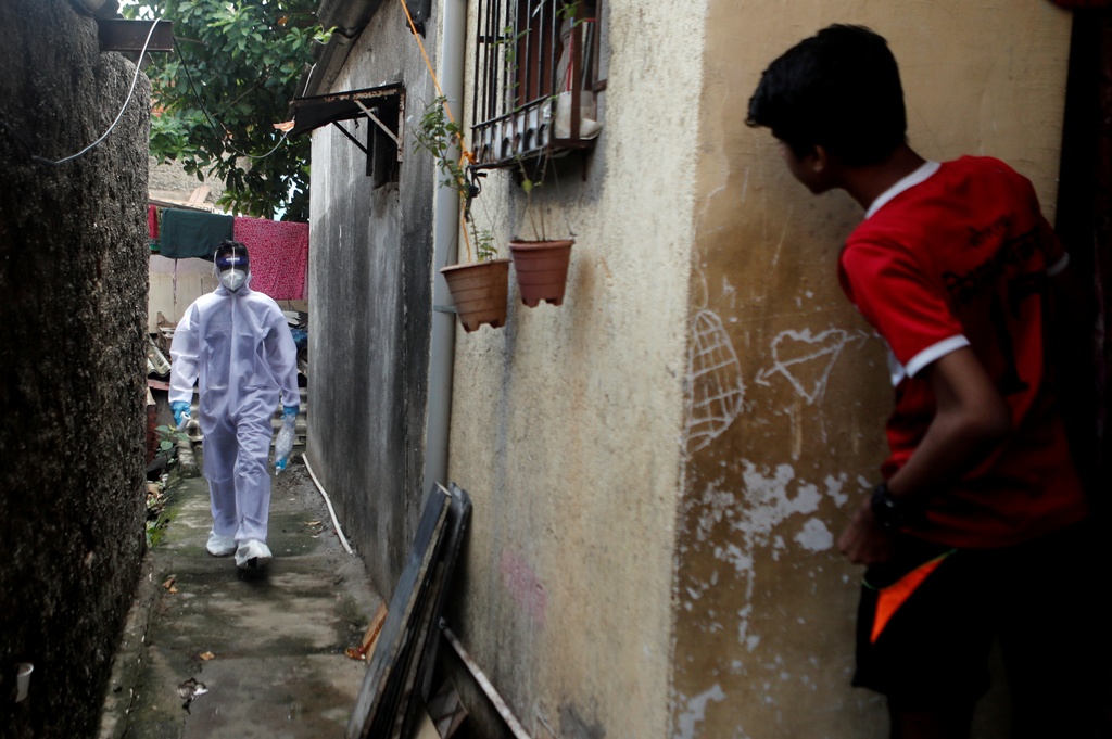 A healthcare worker wearing personal protective equipment (PPE) walks in an alley of a slum area during a check-up camp for the coronavirus disease (COVID-19) in Mumbai, India June 27, 2020. REUTERS/Francis Mascarenhas