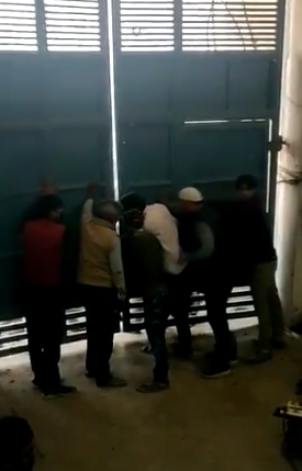 ताहिर हुसैन द्वारा पत्रकार राजदीप सरदेसाई को दिए गए एक वीडियो में कुछ लोग ताहिर के घर का दरवाजा टूटने से बचाने के लिए अंदर से उसे इस तरह पकडे हुए नजर आते हैं. (साभार: ट्विटर/वीडियोग्रैब)