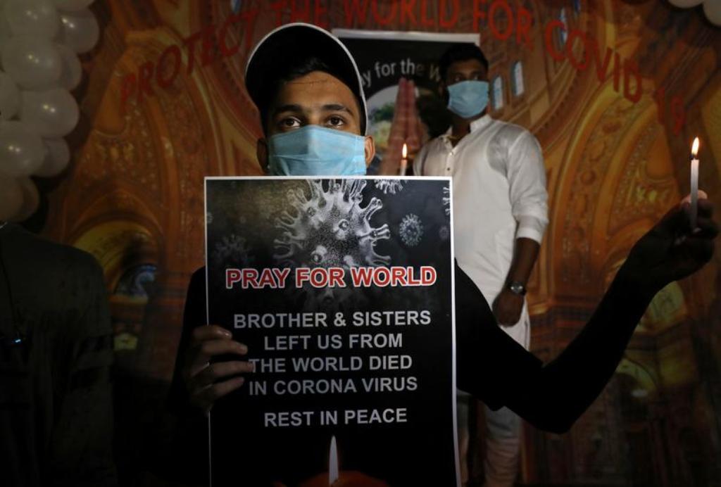 A man wearing a protective face mask holds a placard and a candle during a vigil for the people from around the world, who died due to the coronavirus disease (COVID-19), in Kolkata, India, September 23, 2020. REUTERS/Rupak De Chowdhuri