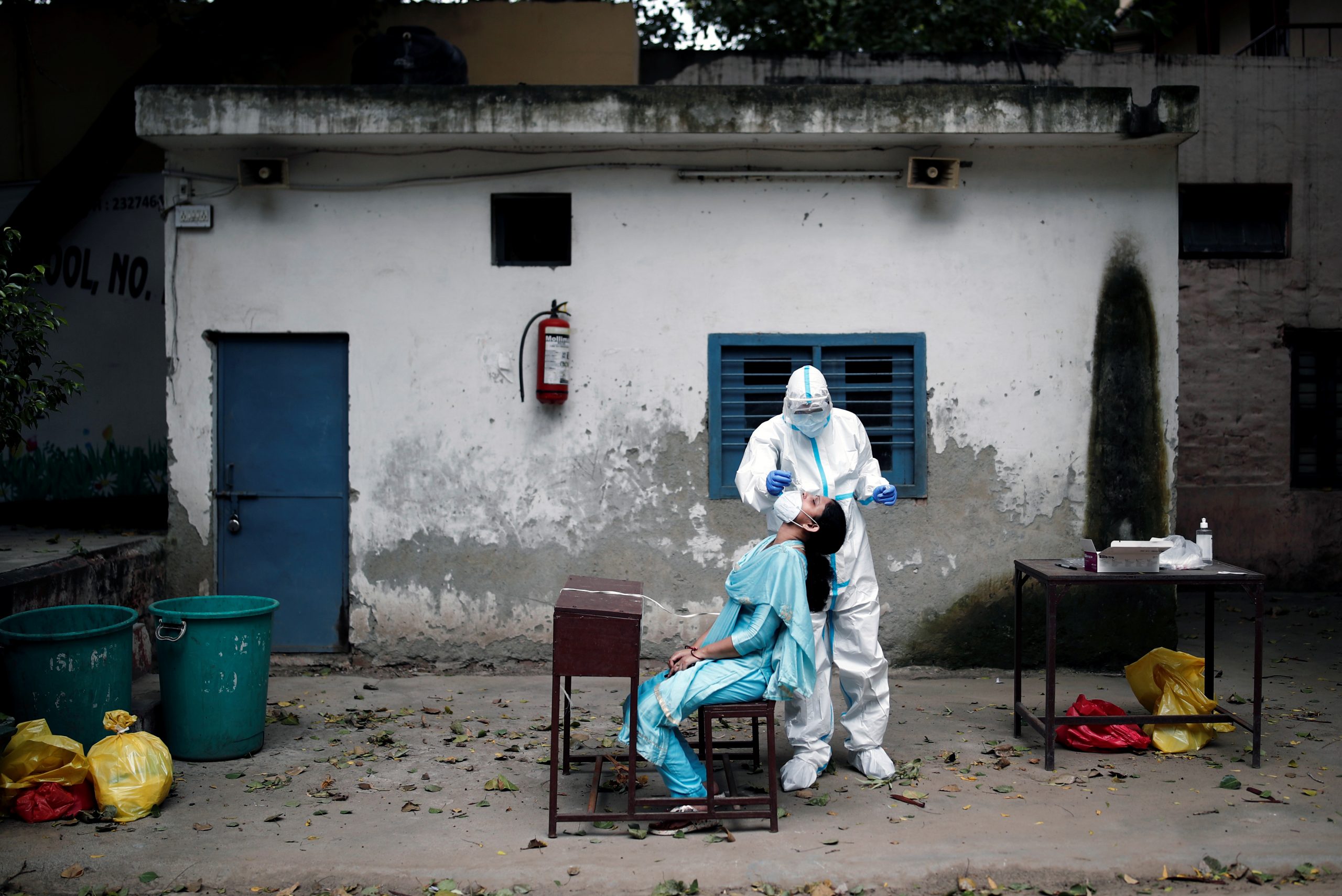 A health worker in personal protective equipment (PPE) collects a sample using a swab from a person at a school which was turned into a centre to conduct tests for the coronavirus disease (COVID-19), amidst the spread of the disease, in New Delhi, India, August 6, 2020. REUTERS/Adnan Abidi