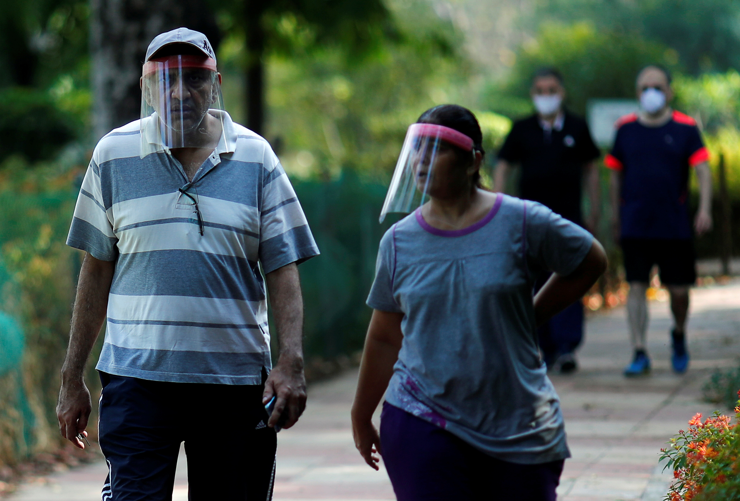 FILE PHOTO: People wearing protective face shields walk inside a park after few restrictions were lifted, during an extended nationwide lockdown to slow the spread of the coronavirus disease (COVID-19), in New Delhi, India, May 31, 2020. REUTERS/Adnan Abidi