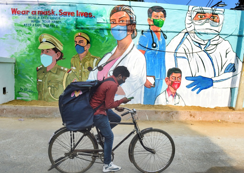 New Delhi: A cyclist rides past a mural, honouring the warriors of COVID-19, in New Delhi, Monday, Dec. 7, 2020. (PTI Photo/Manvender Vashist)(PTI07-12-2020 000152B)