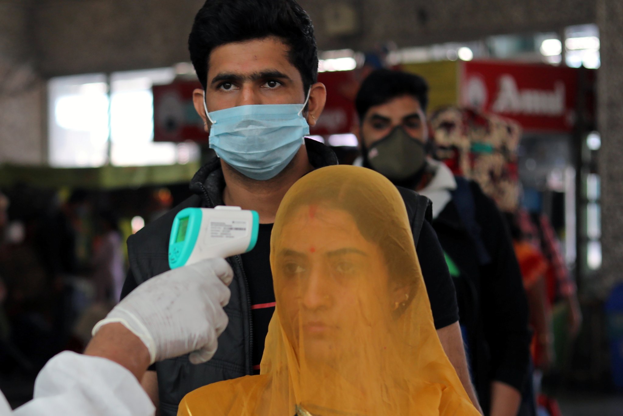 A health worker in personal protective equipment (PPE) checks the temperature of passengers amid the spread of the coronavirus disease (COVID-19), at a railway station in Mumbai, India, December 19, 2020. REUTERS/Francis Mascarenhas