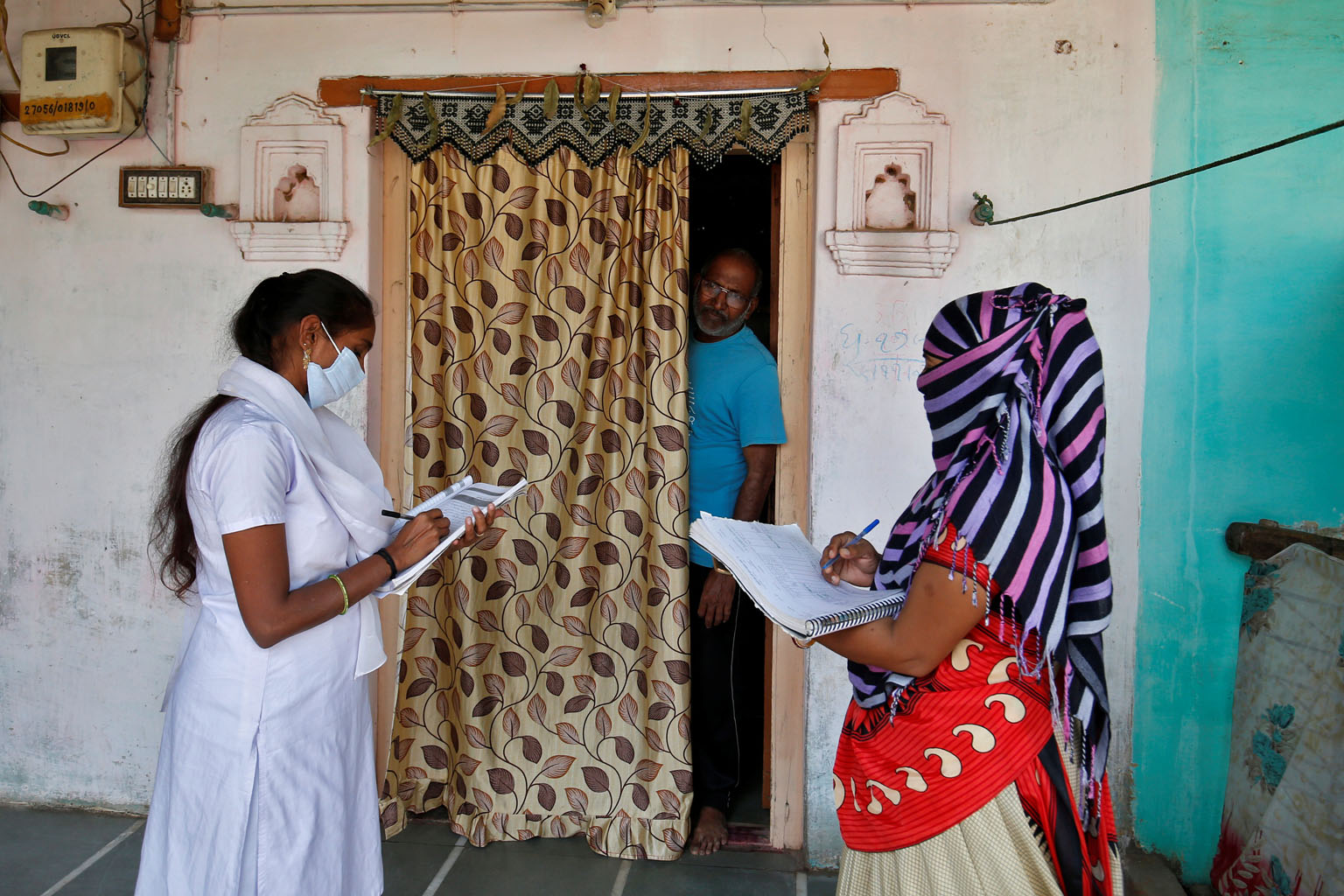 Health workers collect personal data from a man as they prepare a list during a door-to-door survey for the first shot of COVID-19 vaccine for people above 50 years of age and those with comorbidities, in a village on the outskirts of Ahmedabad, India, December 14, 2020. REUTERS/Amit Dave##########x##########