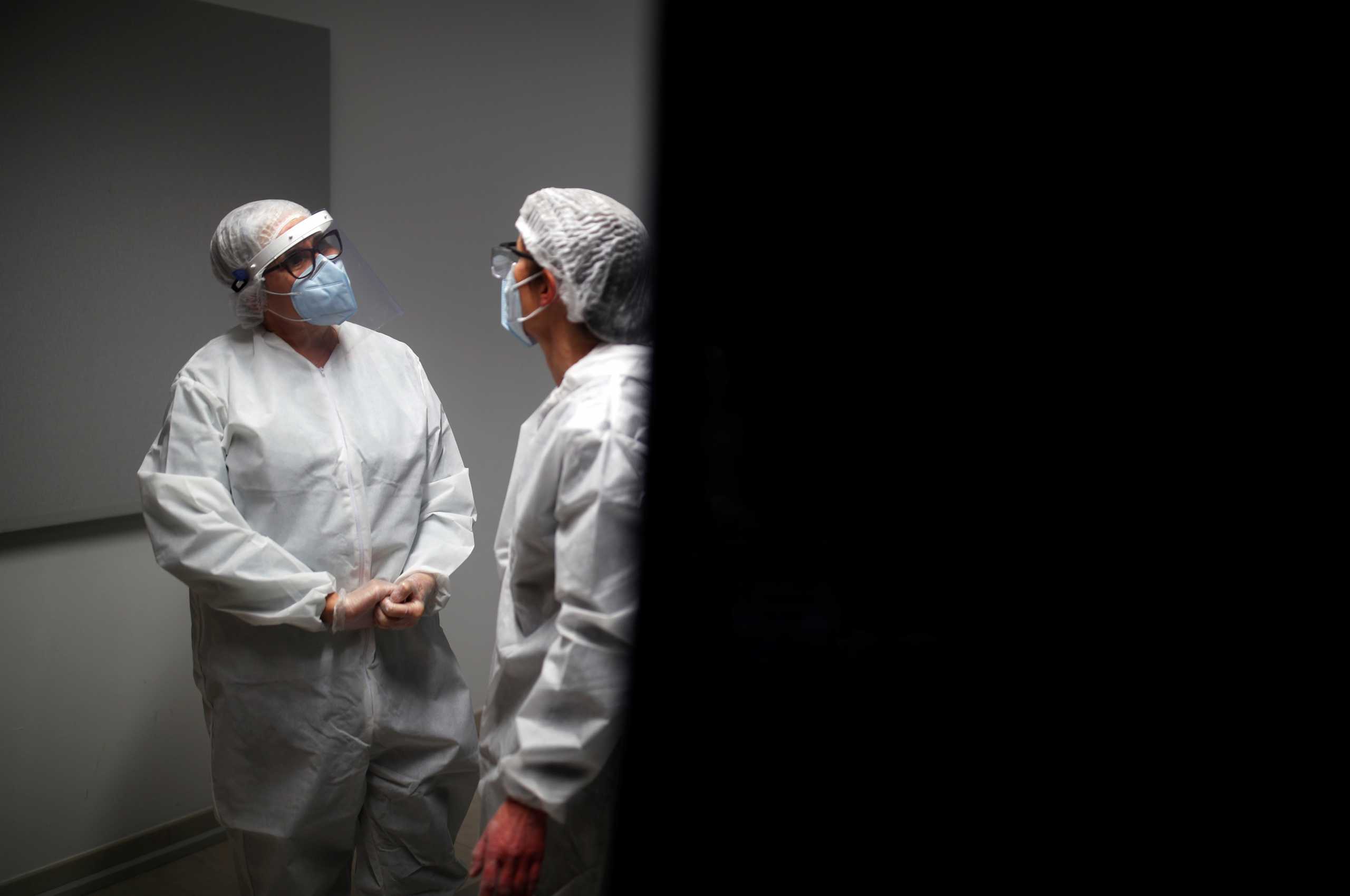 Medical workers, wearing protective suits and face masks, talk as they work at a coronavirus disease (COVID-19) testing centre in Le Bignon, France, December 22, 2020. REUTERS/Stephane Mahe/File Photo