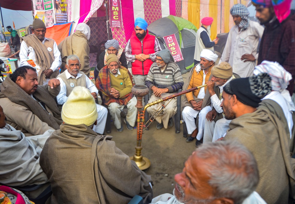 New Delhi: A farmer smokes hookah as others interact at Singhu border during their ongoing protest against the Centres farm reform laws, in New Delhi, Tuesday, Dec. 8, 2020. The farmers have called for a nationwide strike demanding repeal of the agri laws. (PTI Photo/Ravi Choudhary)(PTI08-12-2020 000040B)
