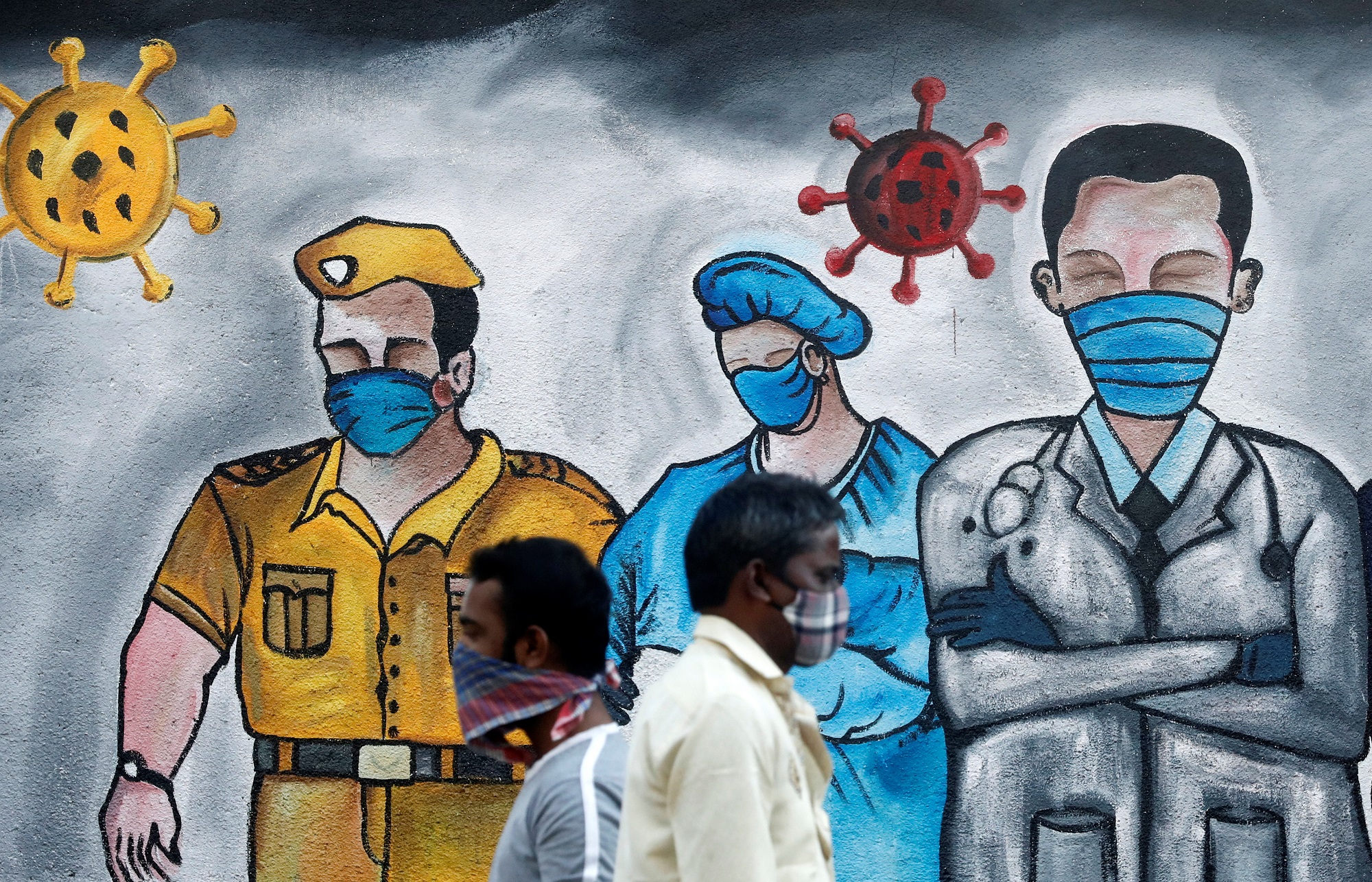 Men walk past a mural of frontline workers amid the spread of the coronavirus disease (COVID-19), in Mumbai on December 21, 2020. (REUTERS)