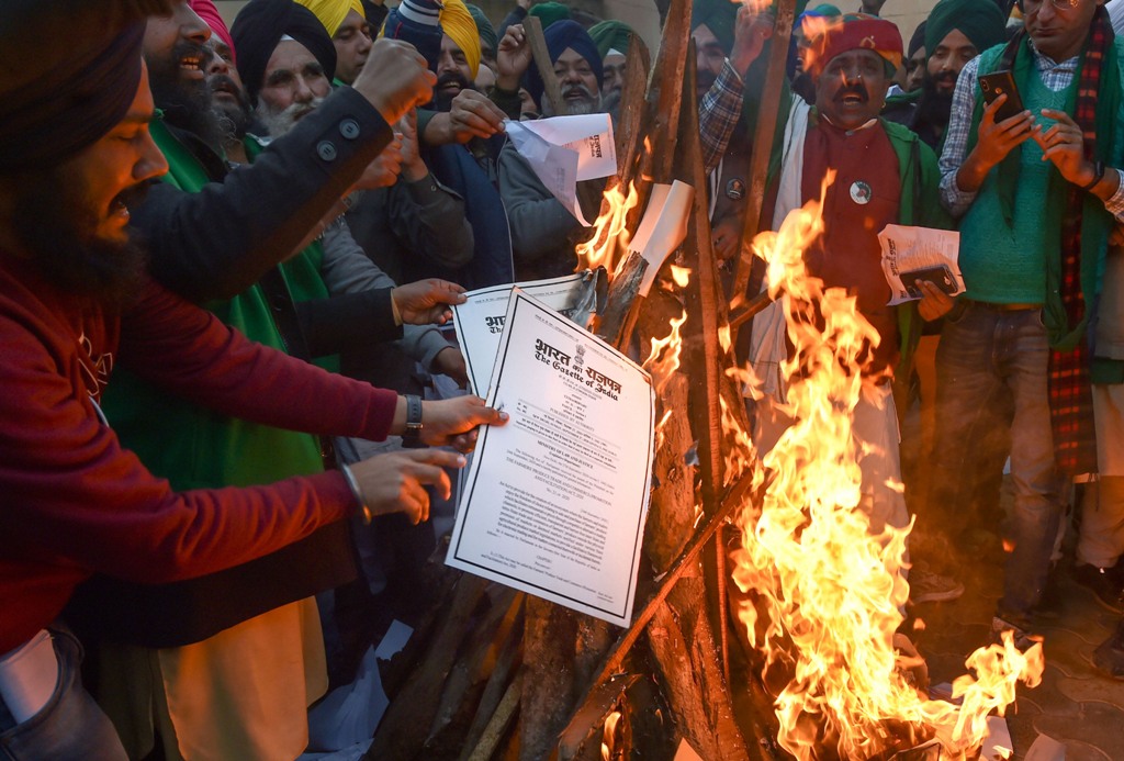 New Delhi: Farmers burn copies of the new farm laws as they celebrate Lohri festival during their ongoing protest against the central government, at Singhu border in New Delhi, Wednesday, Jan. 13, 2021. (PTI Photo/Manvender Vashist)(PTI01 13 2021 000275B)