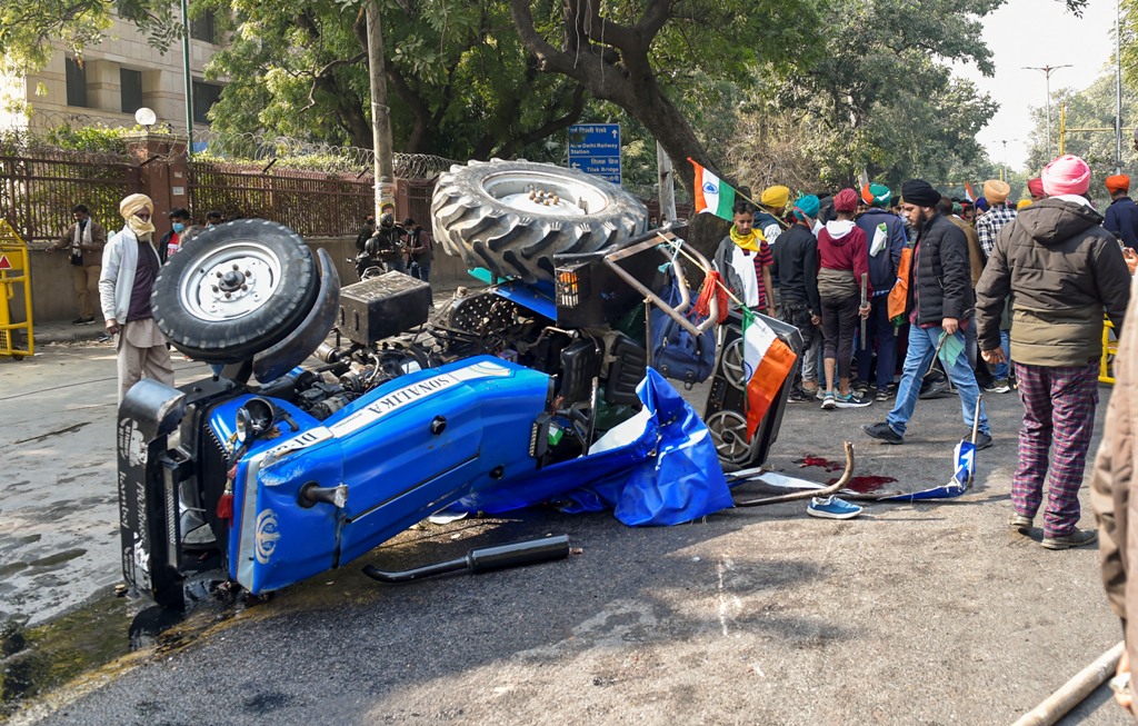New Delhi: Farmers stand next to an overturned tractor at ITO during their Kisan Gantantra Parade to protest against Centres farm reform laws, on the occasion of 72nd Republic Day, in New Delhi, Tuesday, Jan. 26, 2021. A protesting farmer died after his tractor overturned at Central Delhis ITO. (PTI Photo/Ravi Choudhary)(PTI01 26 2021 000323B)