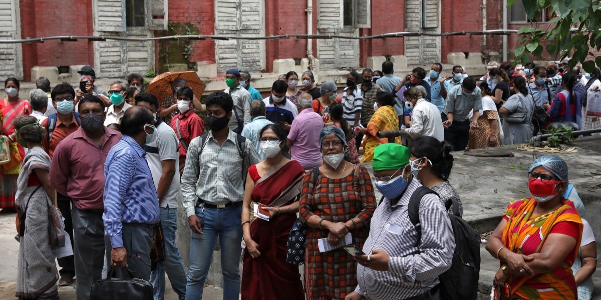 कोलकाता के एक टीकाकरण केंद्र पर खुराक लेने का इंतज़ार करते लोग. (फोटो: रॉयटर्स)